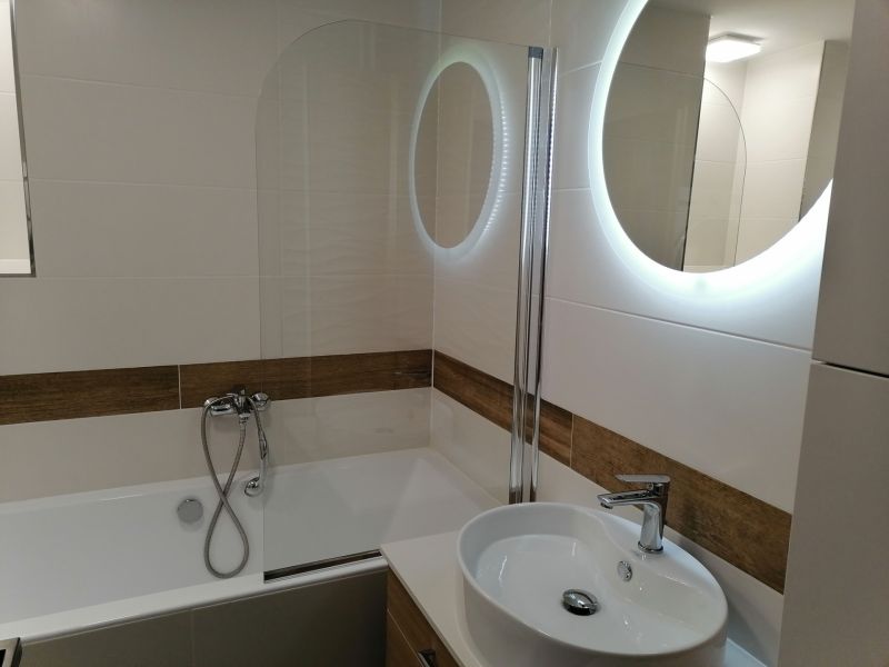 A bathroom with a bathtub, sink, and mirror in a 2-room apartment.