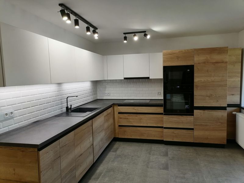 Modern kitchen in a 2-room apartment with white tiles and wood decor.