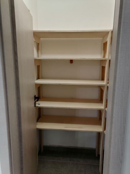 Shelf space in a 2-room apartment with wooden decor doors and flooring.