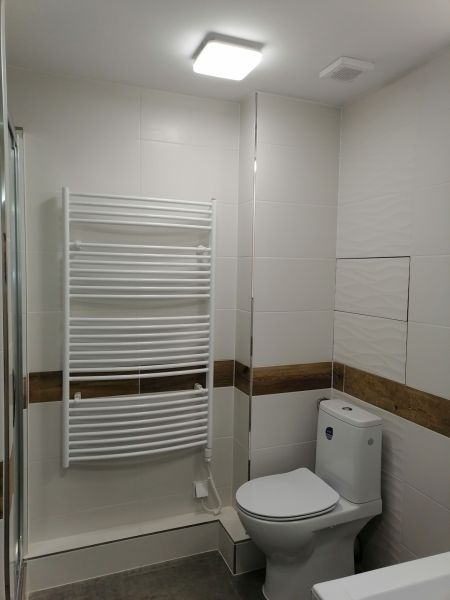 Bathroom in a 2-room apartment, with ceramic tiles and a heating unit on the wall.