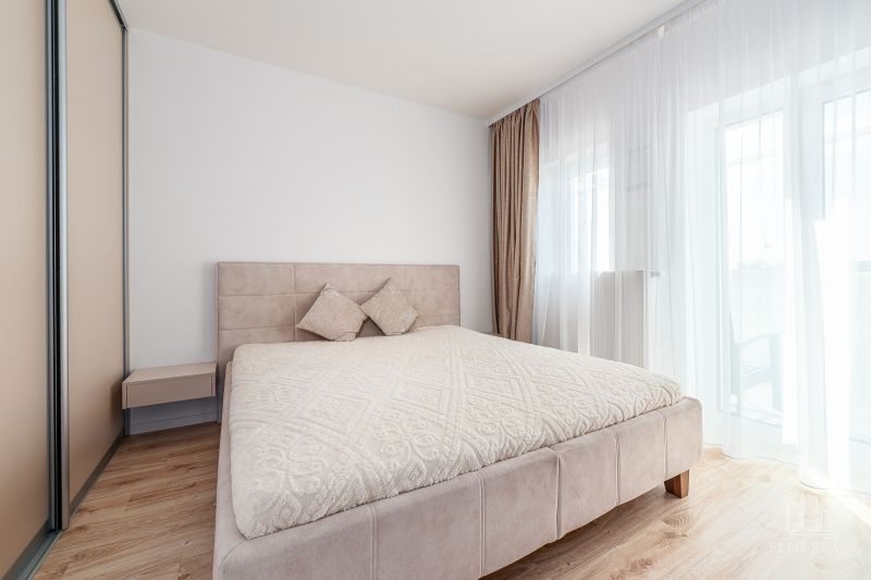 Bedroom with a large bed and a wooden decor floor in a 2-room apartment.