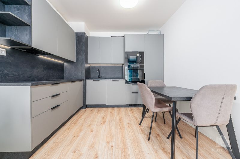 A kitchen in a 2-room apartment with a wooden decor floor and stylish furniture.