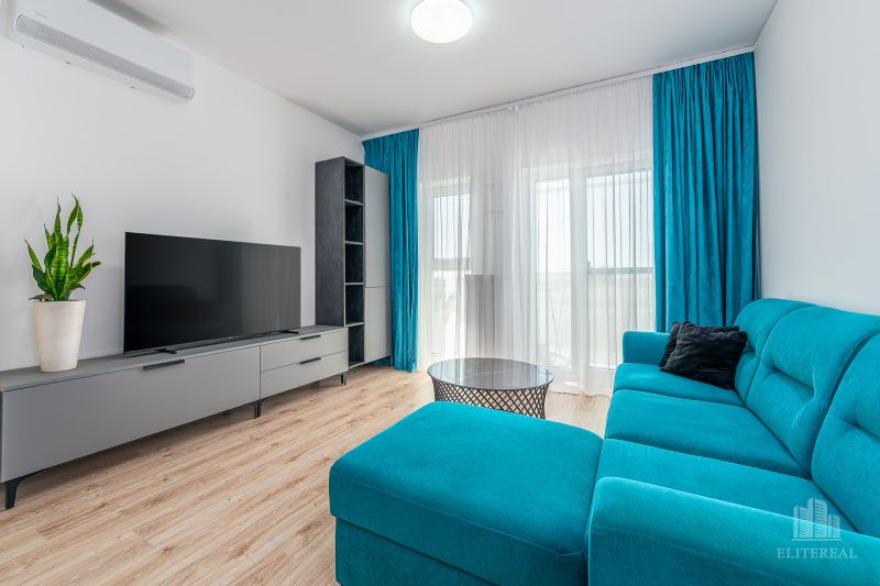 Living room with a turquoise sofa, television, and wooden decor flooring.