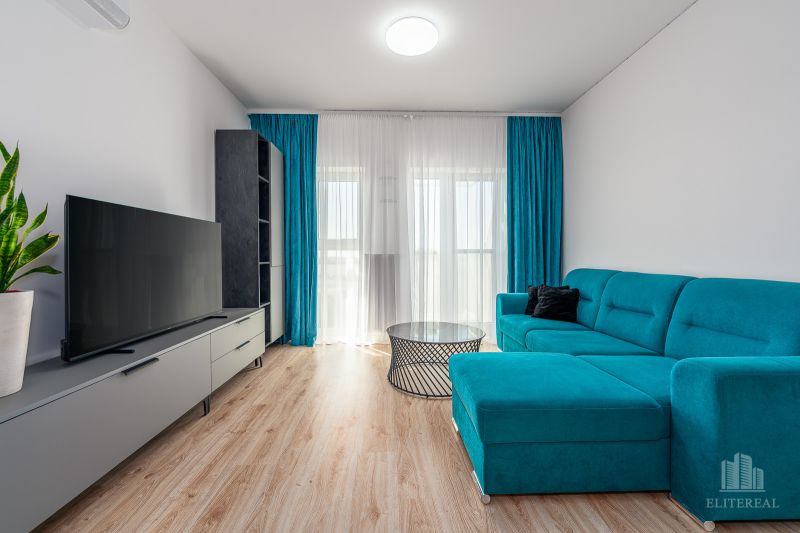 Living room in a two-room apartment with a wooden-patterned floor and a blue couch.