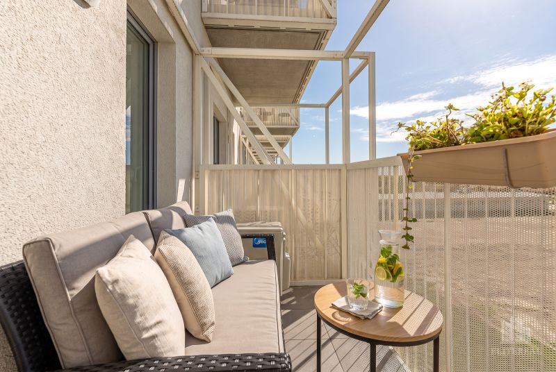 Balcony in a 2-room apartment, comfortable sofa, table, flower pots, relaxing environment.