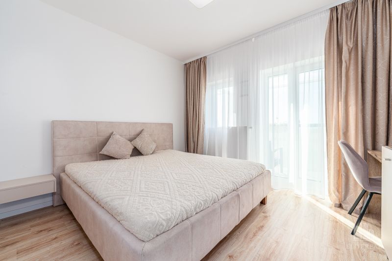 A bright bedroom with a large bed and a wooden decor floor in a 2-room apartment.