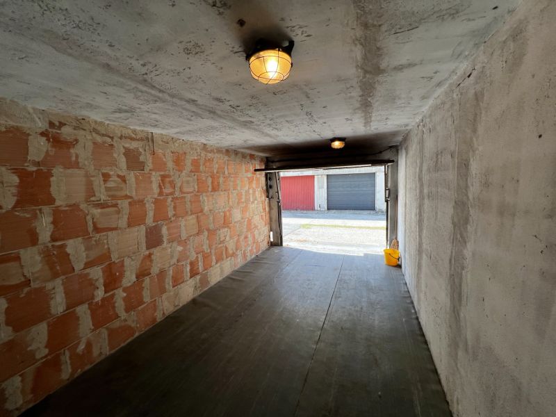 The interior of a garage with unfinished walls and a floor with a wooden decor.