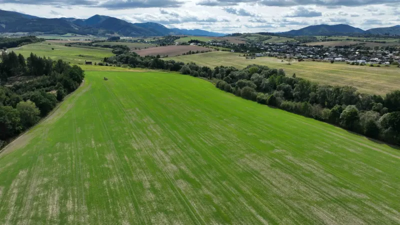Agricultural and forest lands around Žilina with green fields and forests on the horizon.