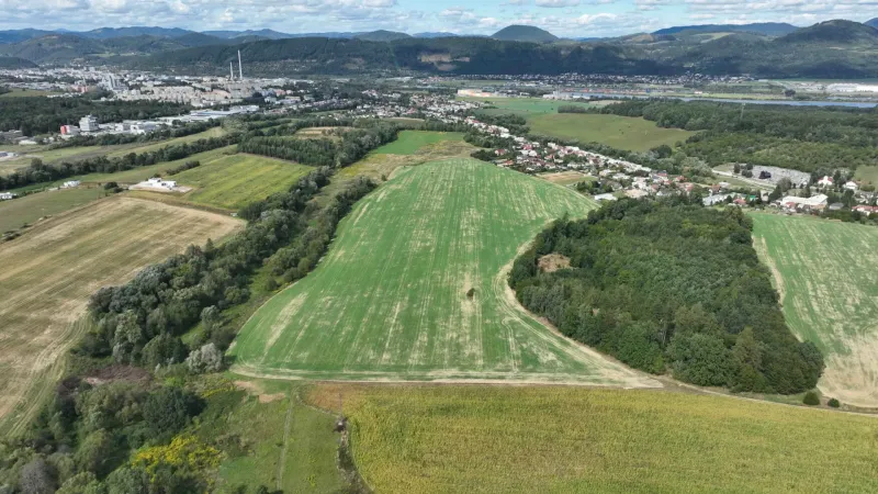 Aerial view of agricultural and forest land around Žilina, surrounded by a village.