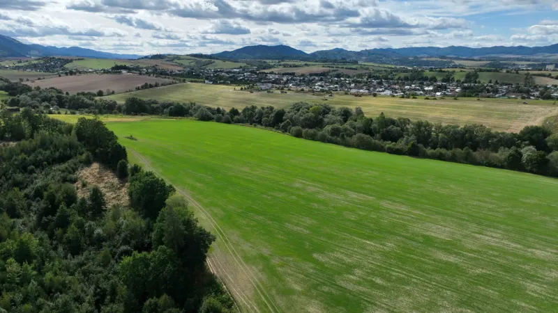 Extensive agricultural and forest lands around Žilina, with views of the hills and the village.