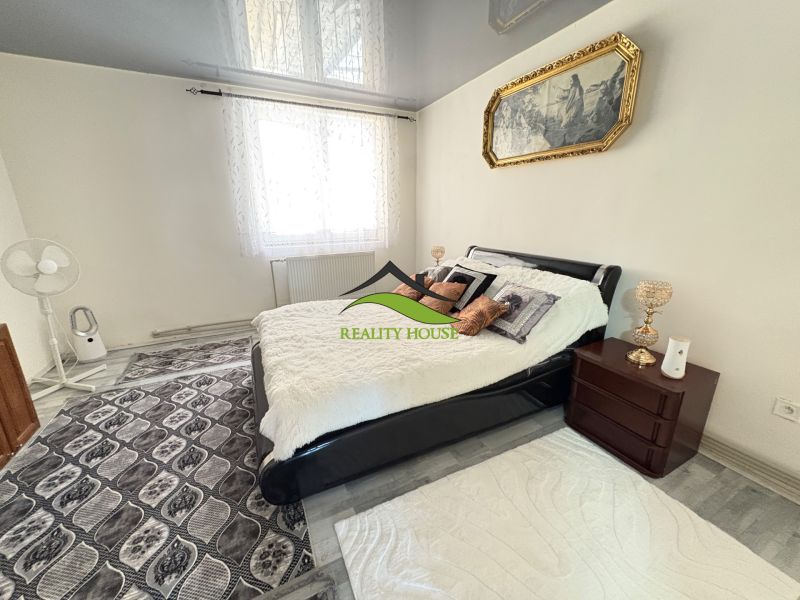 Bedroom in a family house with a bed, carpet, and a picture on the wall.