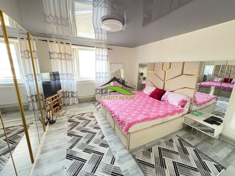 A bedroom in a family house with a mirrored wardrobe, patterned carpets, and a decorative ceiling.