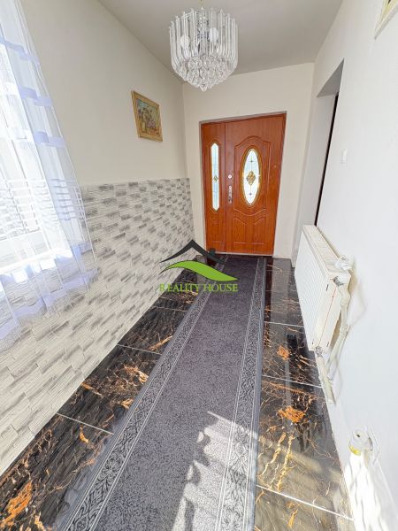 A hallway in a family house with distinctive tiles and a chandelier.