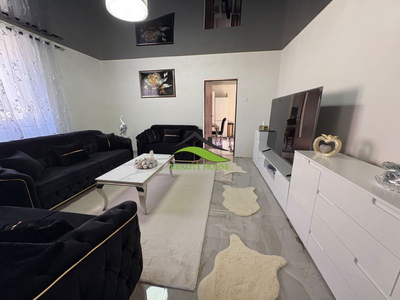 Living room of a family house with dark sofas, white furniture, and decorations.