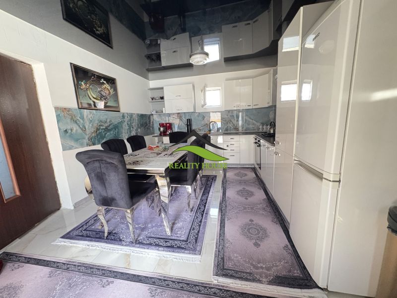 The kitchen of a family house with a dining table, dark chairs, and decorative tiling.