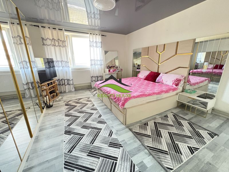 Bright bedroom in a family house with a pink bed and a wooden decor floor.