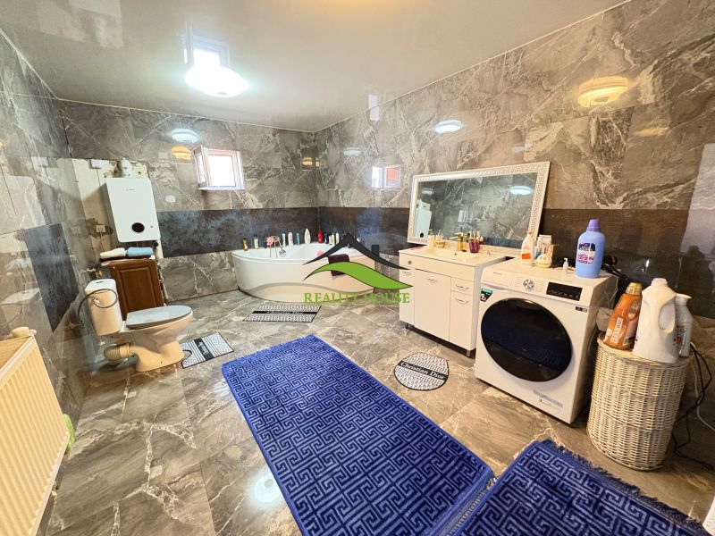 A family house bathroom with a bathtub, toilet, and washing machine on a floor with a wooden decor.