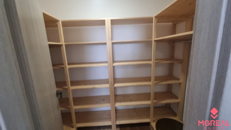 A wardrobe in a 2-room apartment with wooden shelves for storing clothes.