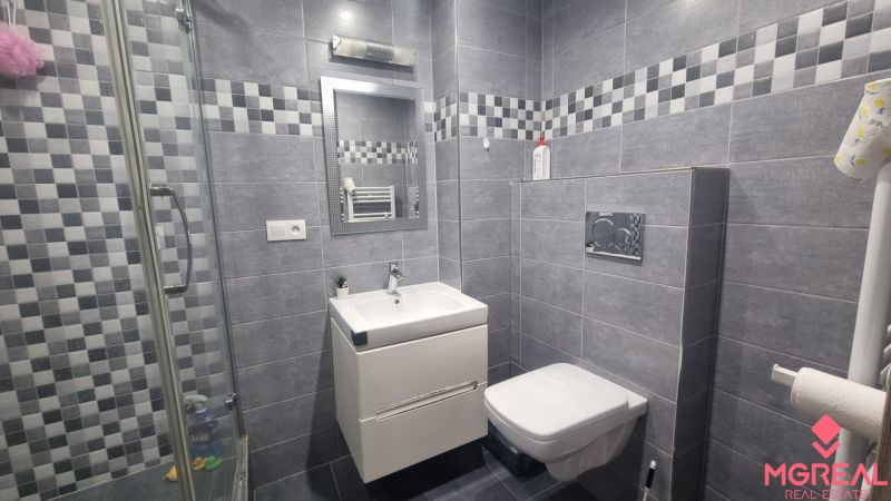 A bathroom in a 2-room apartment with tiles and a shower, modern equipment.