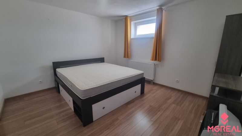 Bedroom with a bed, window, and yellow curtains, floor with wooden decor.
