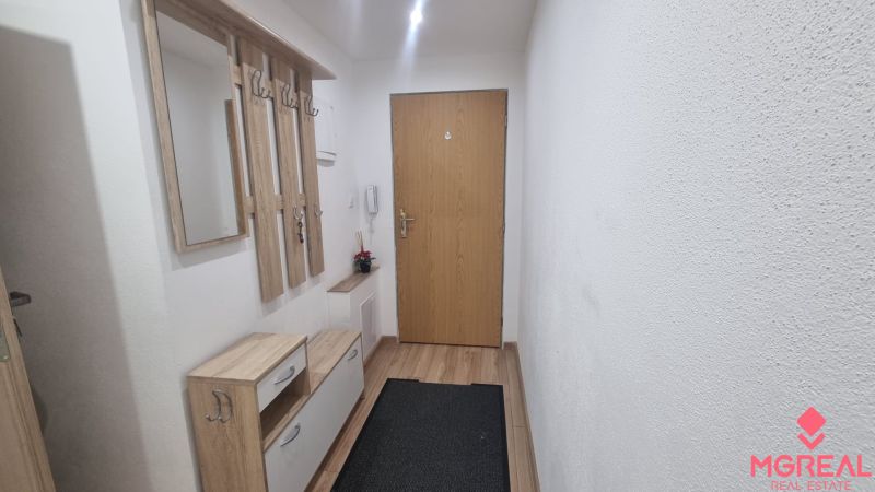 Entrance hallway of a 2-room apartment with a coat rack and flooring with a wooden decor.