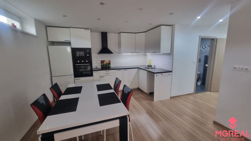 A kitchen in a 2-room apartment with a wooden decor floor and white furniture.