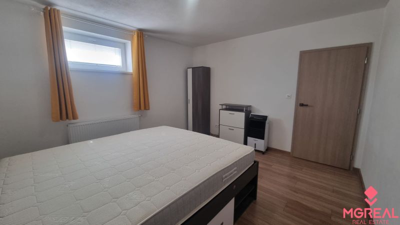 Bedroom in a 2-room apartment with wood-patterned flooring and storage space.
