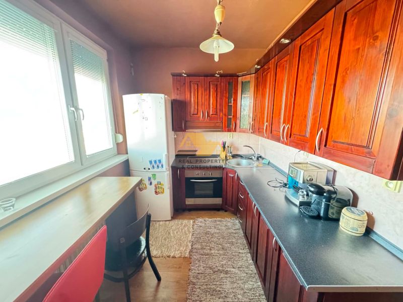 A kitchen with appliances and wooden decor in a 3-room apartment.