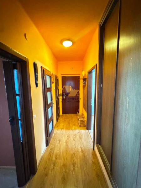 A hallway in a 3-room apartment with a wooden decor floor and wooden doors.