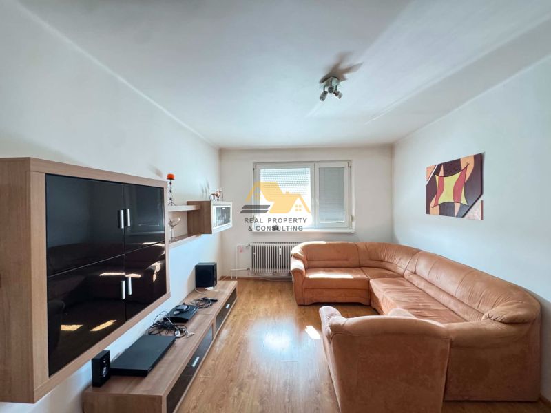 Living room with a light sofa, furniture, and flooring with a wood decor in a 3-room apartment.