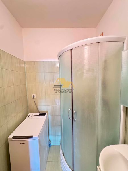 A bathroom with a washing machine and a shower in a 3-room apartment.