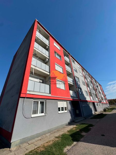 Apartment building in Bajč on Bajč Street with red elements and balconies.