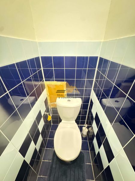 A bathroom in a 3-room apartment with dark blue tiles and white sanitary ware.