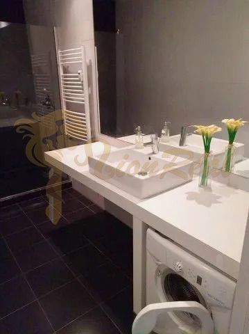 Bathroom with black floor, sink, and washing machine in a 2-room apartment.