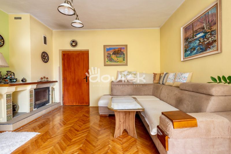 Living room in a family house, wooden decor flooring, fireplace, sofa, paintings on the walls.