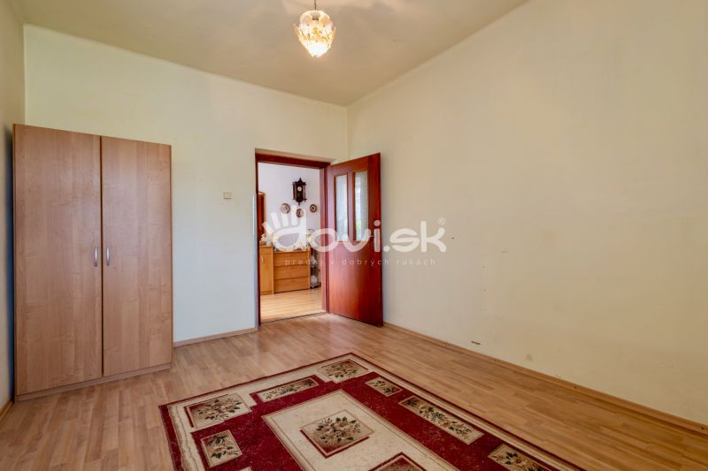 A room in a family house with a wooden decor floor, a carpet, and a wardrobe.