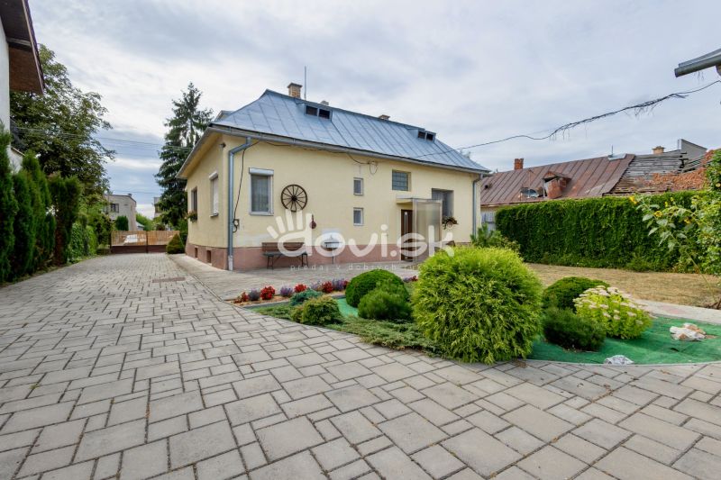 A family house on Topolianska Street in Michalovce with a landscaped garden and a paved road.
