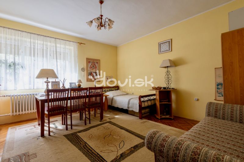 Living room in a family house with a table, chairs, and a sofa. Light walls and a window.