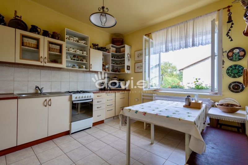 A kitchen in a family house with white cabinets, a stove, and a large window.