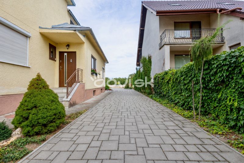 A view of a family house on Topolianska Street in Michalovce with paving and greenery.