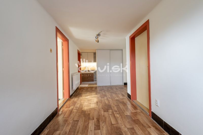 A hallway in a family house with a wooden decor floor and orange door frames.