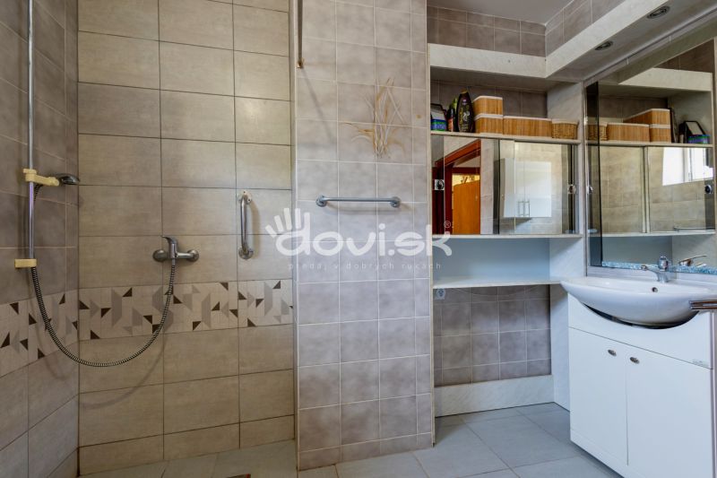 Bathroom with tiles, shower, and sink in a family house.
