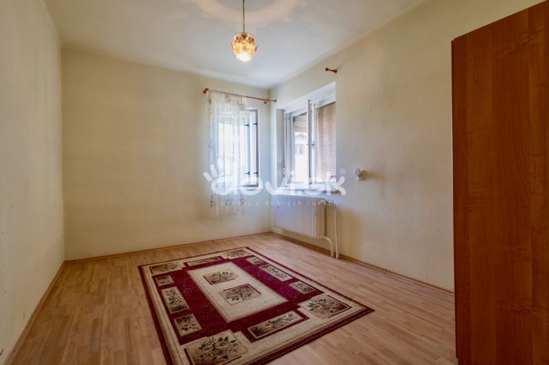 A room in a family house with a wooden decor floor and a carpet on the edge.