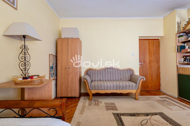 Living room in a family house with a sofa, a wardrobe, and a floor with a wooden decor.