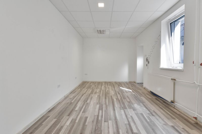 Commercial space with a large window, white walls, and a floor with a wood decor.