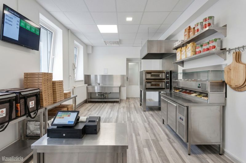 Kitchen commercial space with stainless steel equipment, storage, and a cash register system on a wooden decor floor.