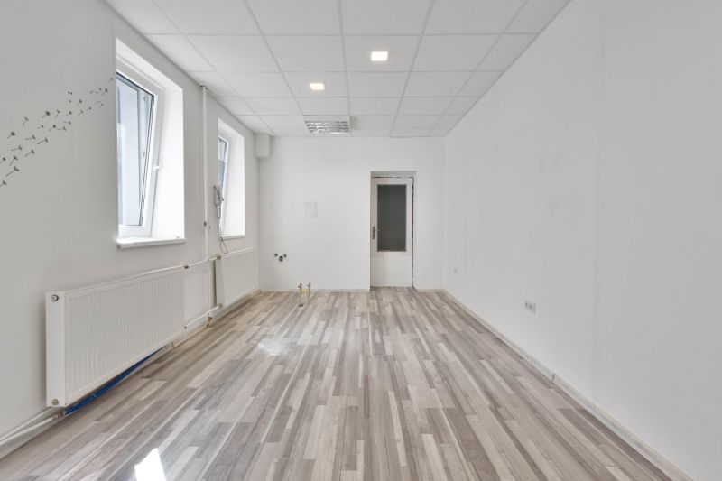 Empty commercial space with wood-patterned flooring and two windows.