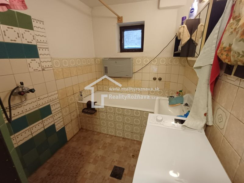A bathroom in a family house with a bathtub, a washing machine, and tiles in vibrant colors.