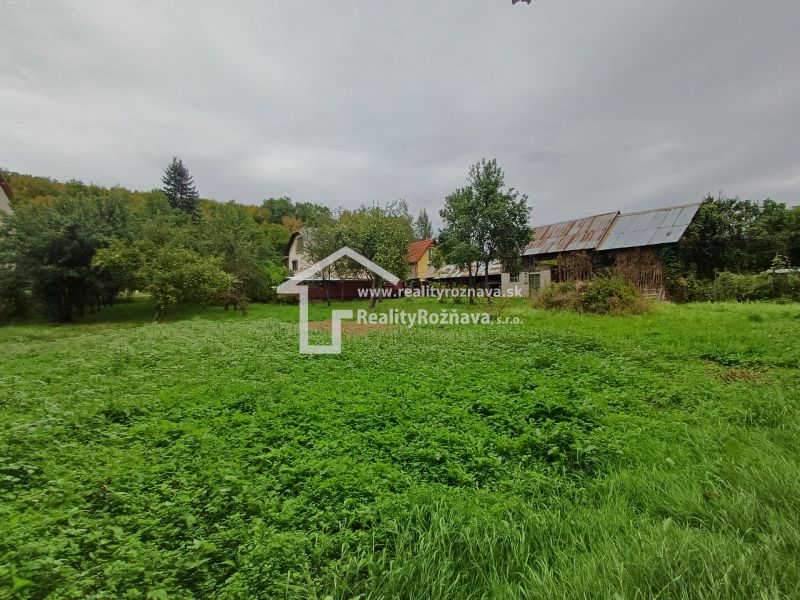 A family house in Drnava surrounded by greenery and trees, with an older building behind it.