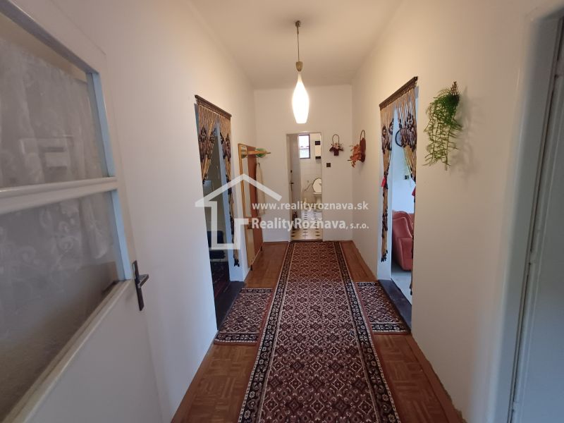 A hallway in a family house with a wooden decor floor and a carpet.